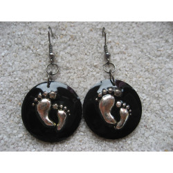 Fancy earrings, small feet, on a black resin background