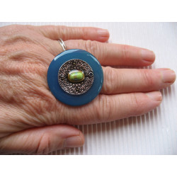 Large ring, silver metal charm and marbled stone, on blue resin background