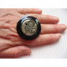 Very large frozen time charm ring on a black background in resin
